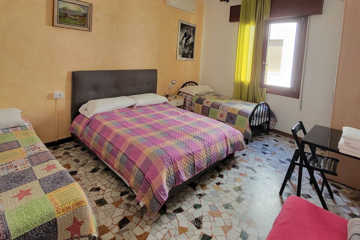 Une chambre avec deux lits, une petite table, une chaise et une fenêtre avec des rideaux.