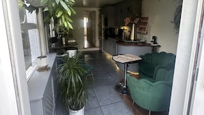 Una cocina moderna con zona de comedor, que incluye un sofá verde, una mesita y plantas en macetas.