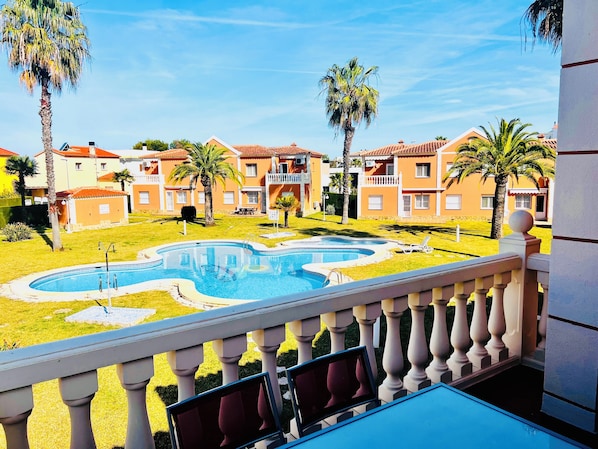 A pool area with a curved design, surrounded by a well-maintained lawn and palm trees.
