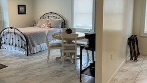 A bedroom with a bed, bedside table, chair, and a desk with a chair.