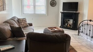 A living room with a sofa, a coffee table, a fireplace, and a television.
