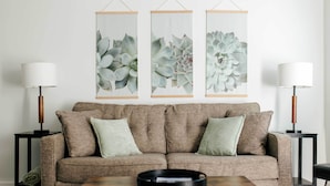 A living room with a brown sofa, two side tables with lamps, and three framed wall art pieces. - Chic Lancaster Vacation Rental, Walkable Location! (Lancaster)