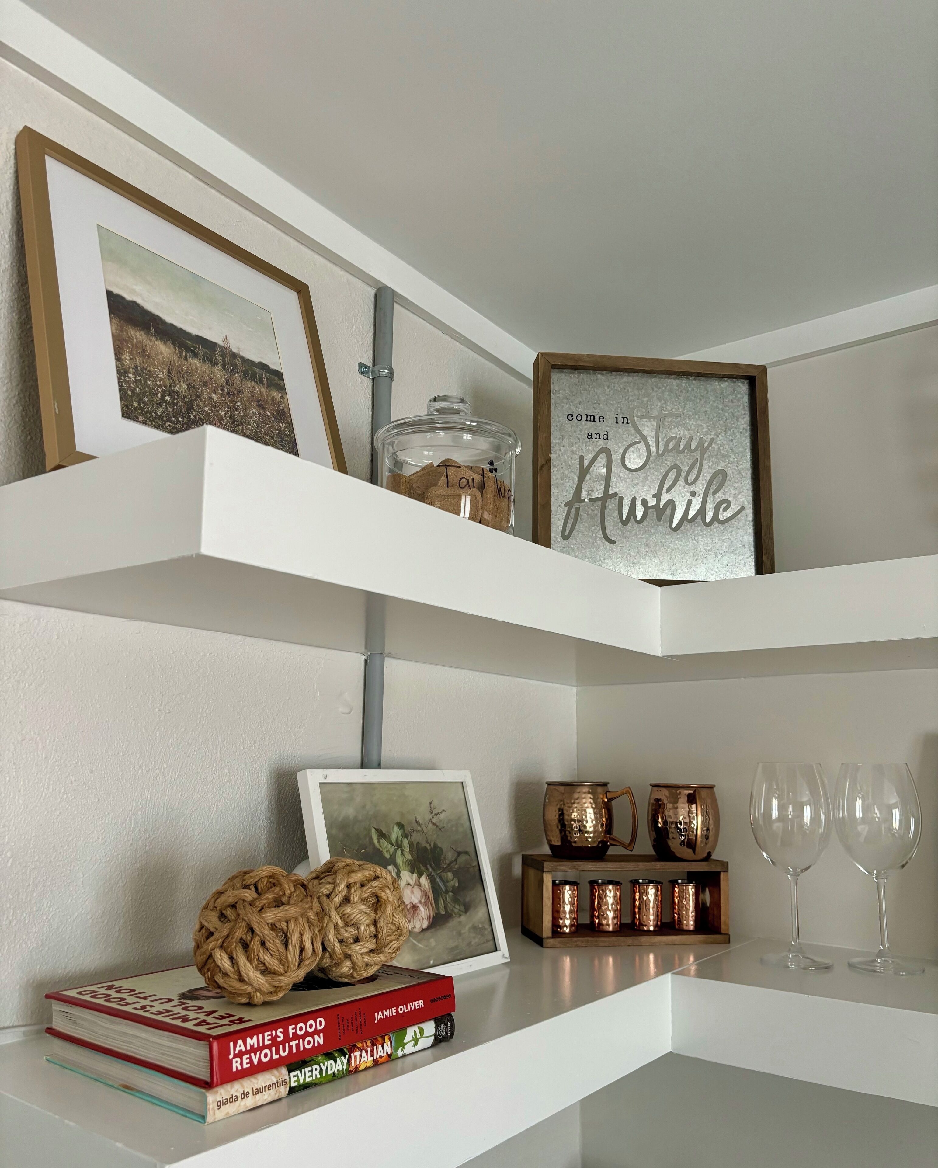 Una estantería con libros, un tarro, un cartel en marco y objetos decorativos.