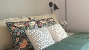 A neatly made bed with patterned pillows and a green bedspread. - Walkable Cottage, Pet Friendly with Fenced Patio (Southern Pines)
