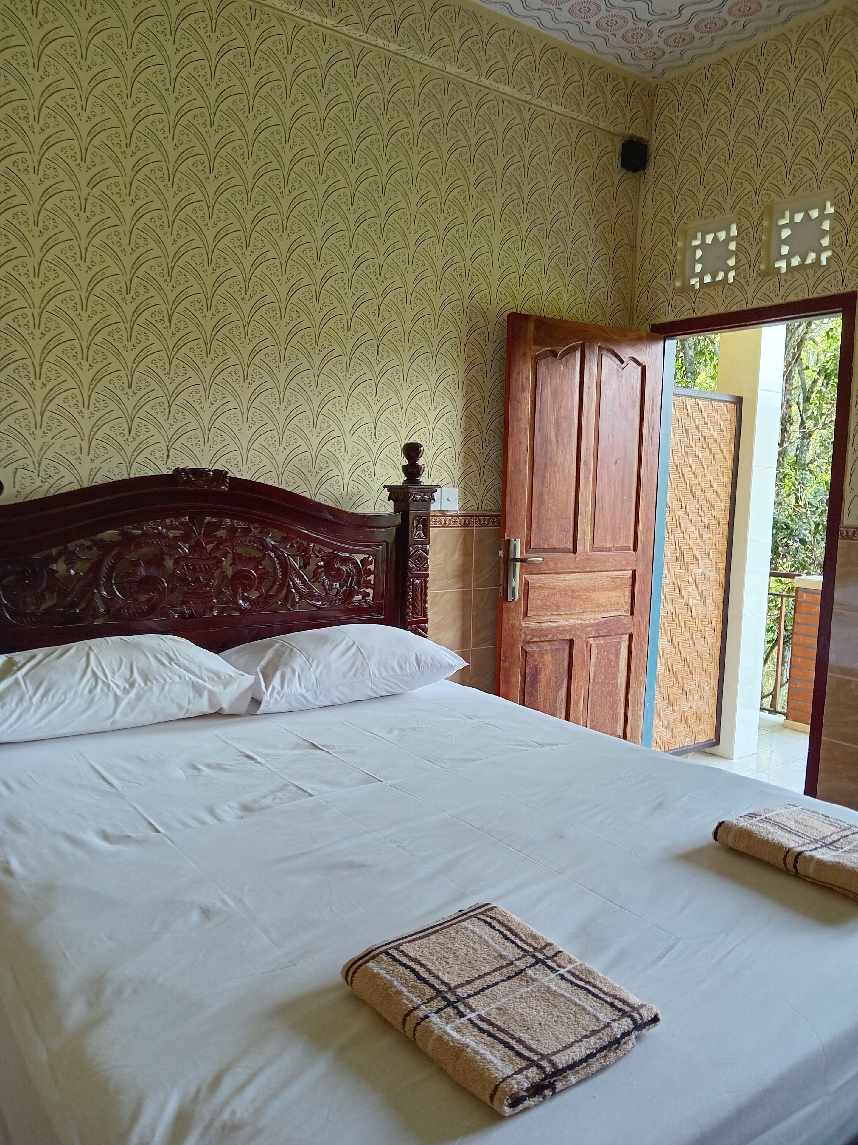 Un dormitorio con cama de madera, ropa de cama blanca y papel tapiz estampado.