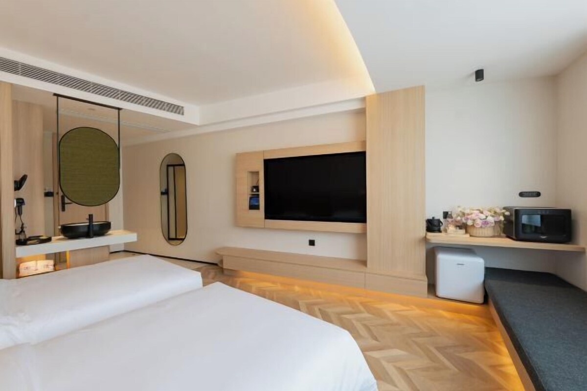 A modern hotel room with a bed, a TV, a small desk, and a microwave.