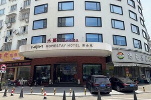 Un edificio de varios pisos con un letrero llamativo del Homestay Hotel.
