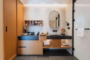 A modern bathroom with a wooden vanity, black countertop, and a large mirror.