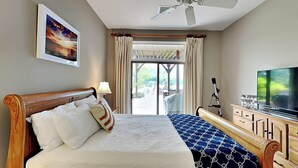 Habitación de hotel con una cama grande, televisión, escritorio con lámpara y vista al exterior.