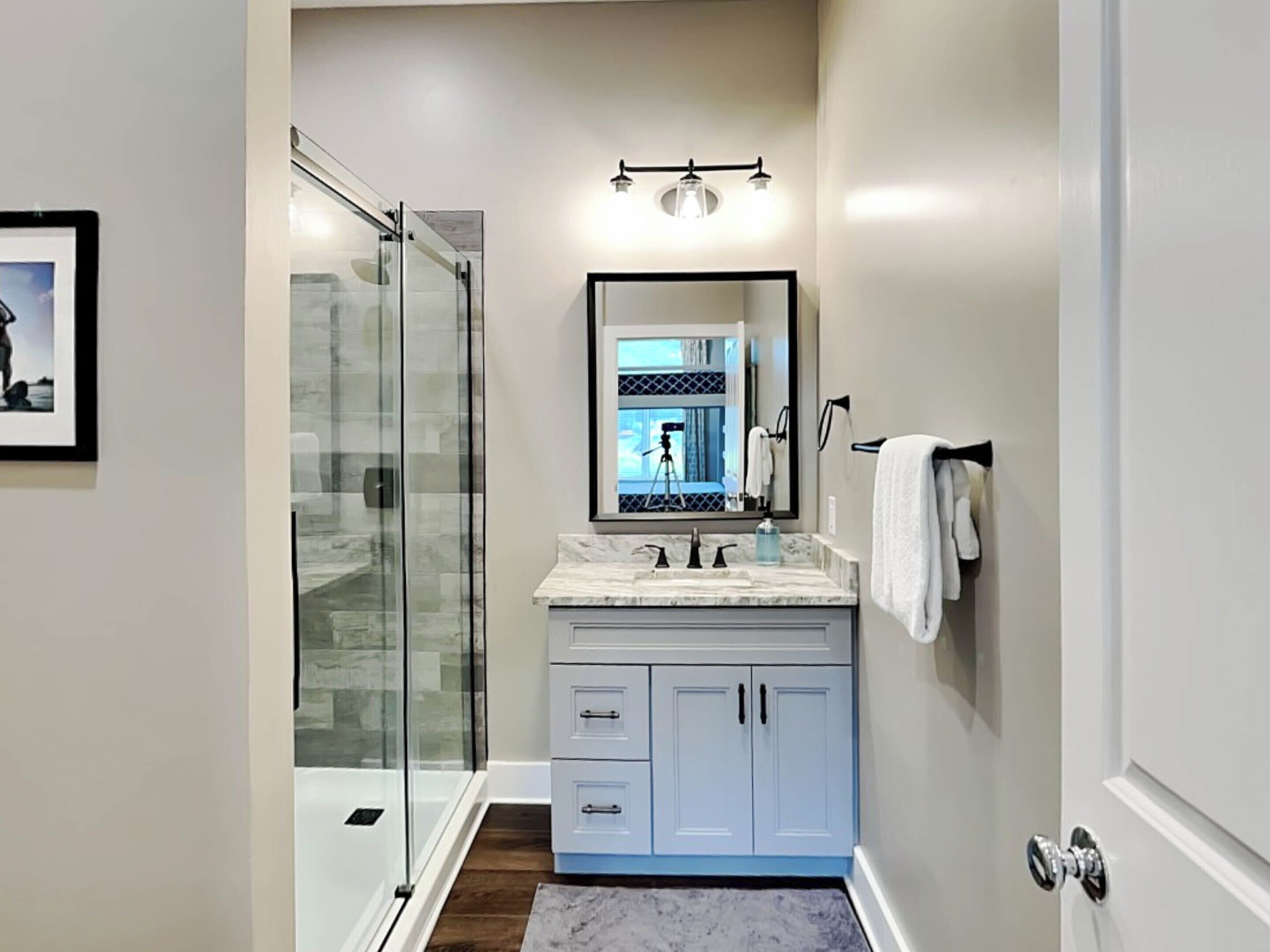 A modern bathroom with a glass shower enclosure, a marble sink, and a large mirror.