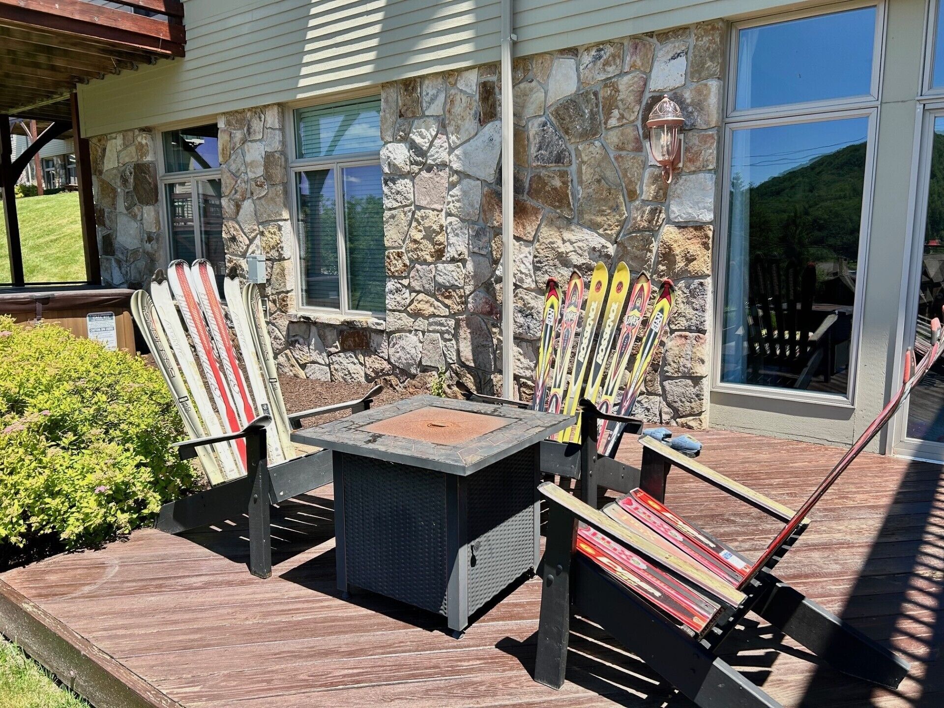 Une terrasse avec un mur en pierre, une table et des chaises.