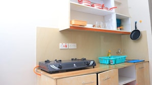 A compact kitchen with a gas stove, a sink, and a countertop with a basket and a frying pan. - Impeccable 1-bed Apartment in Nairobi (Nairobi)
