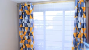 A bathroom with a window, a shower curtain with a geometric pattern, and a towel rack. - Impeccable 1-bed Apartment in Nairobi (Nairobi)