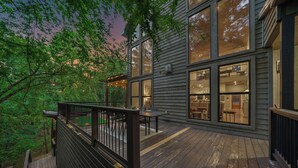 A modern house with a deck, large windows, and a view of the surrounding forest. - Your Family-Fun HQ w/Hot Tub, Firepit, 2 Gamerooms (Broken Bow)