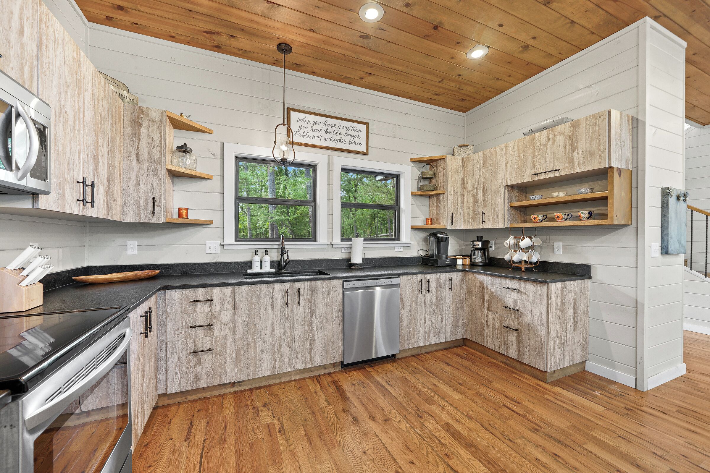 A modern kitchen with wooden cabinets, a dishwasher, and a black countertop.