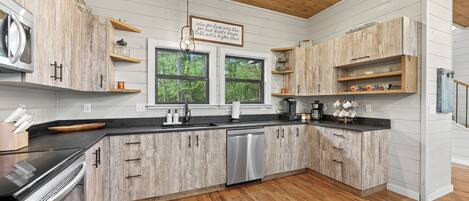 A modern kitchen with wooden cabinets, a dishwasher, and a black countertop.