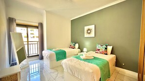 A hotel room with two beds, a large window, a mirror, and a green wall with a picture. - VILAMOURA PRESTIGE 2 WITH POOL by HOMING (Vilamoura)