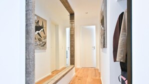 Ein Flur mit Holzboden, weißen Wänden und einer Treppe, die in einen anderen Raum führt.