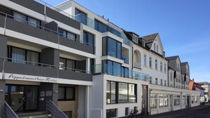 Ein mehrstöckiges Gebäude mit einem Restaurant im Erdgeschoss, das eine Treppe, große Fenster und ein Fahrrad vor der Tür zeigt.