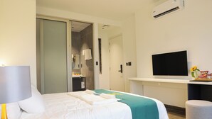A hotel room with a bed, a desk with a flat-screen TV, a mirror, and an air conditioning unit. - Ao Tien Harbour Boutique Hotel (Van Don)