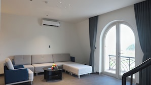 A modern living room with a sofa, armchair, and a coffee table. - Ao Tien Harbour Boutique Hotel (Van Don)