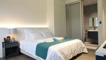 Une chambre d’hôtel comprenant un lit, une table de chevet, une lampe et une salle de bain avec douche et lavabo.
