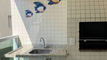 Uma cozinha com bancada de granito, pia de aço inoxidável e azulejos decorativos com tema de peixe na parede.
