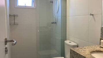 Een badkamer met een douche met glazen wand, een toilet en een wastafel met een granieten blad.