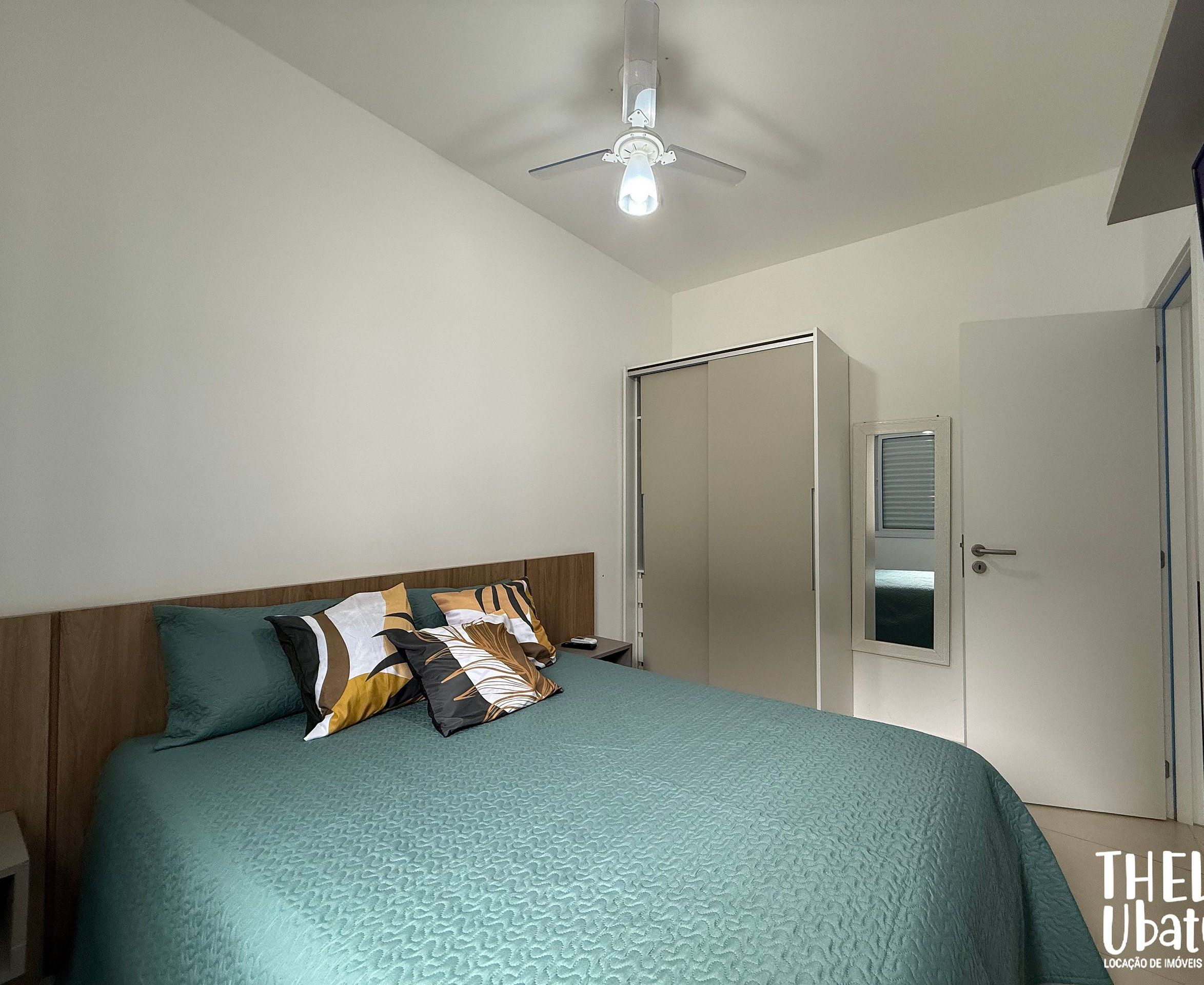 A bedroom with a bed, a wardrobe, a ceiling fan, and a door.
