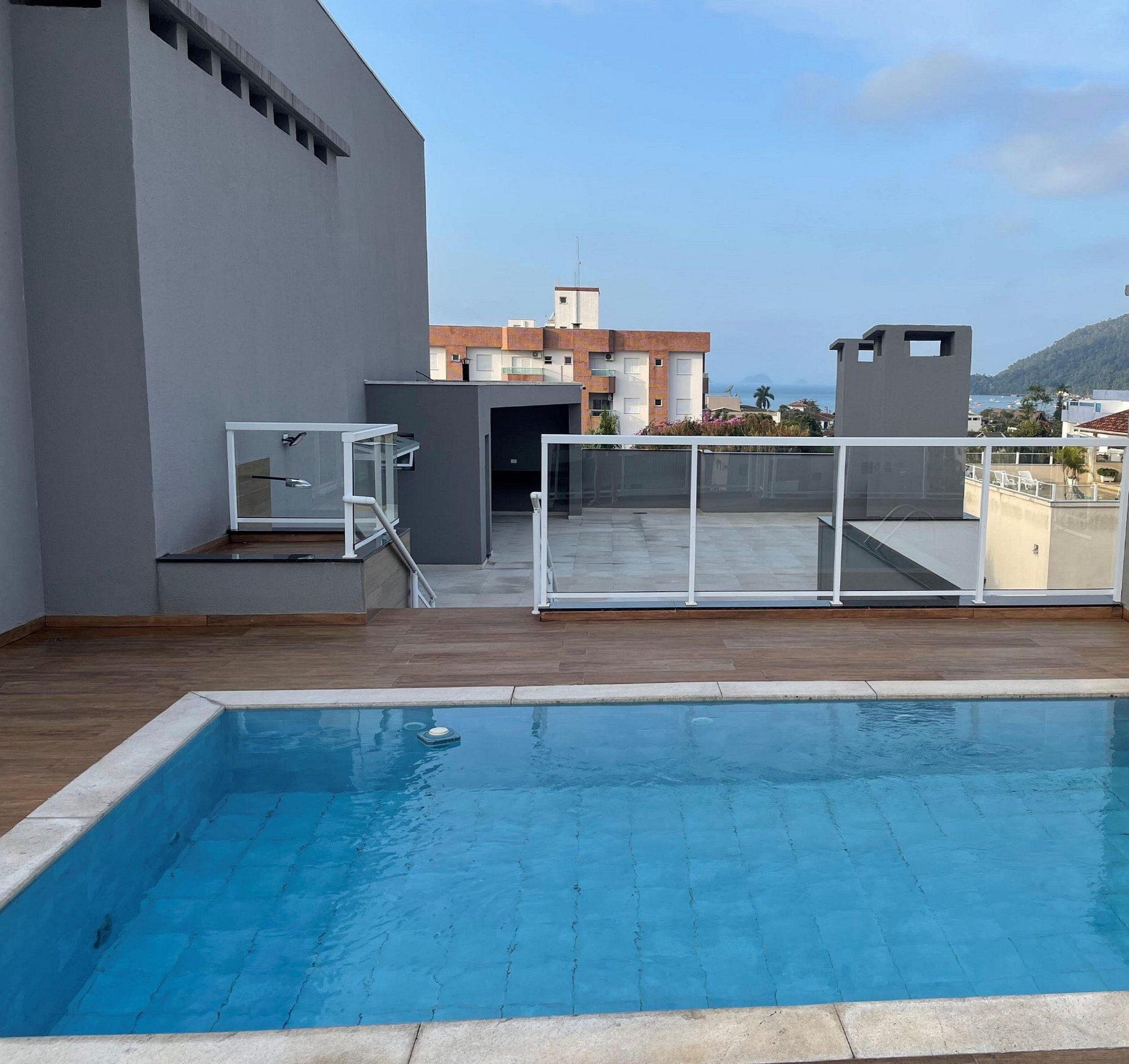 Una piscina en la azotea con vistas despejadas de los edificios circundantes y una montaña distante.