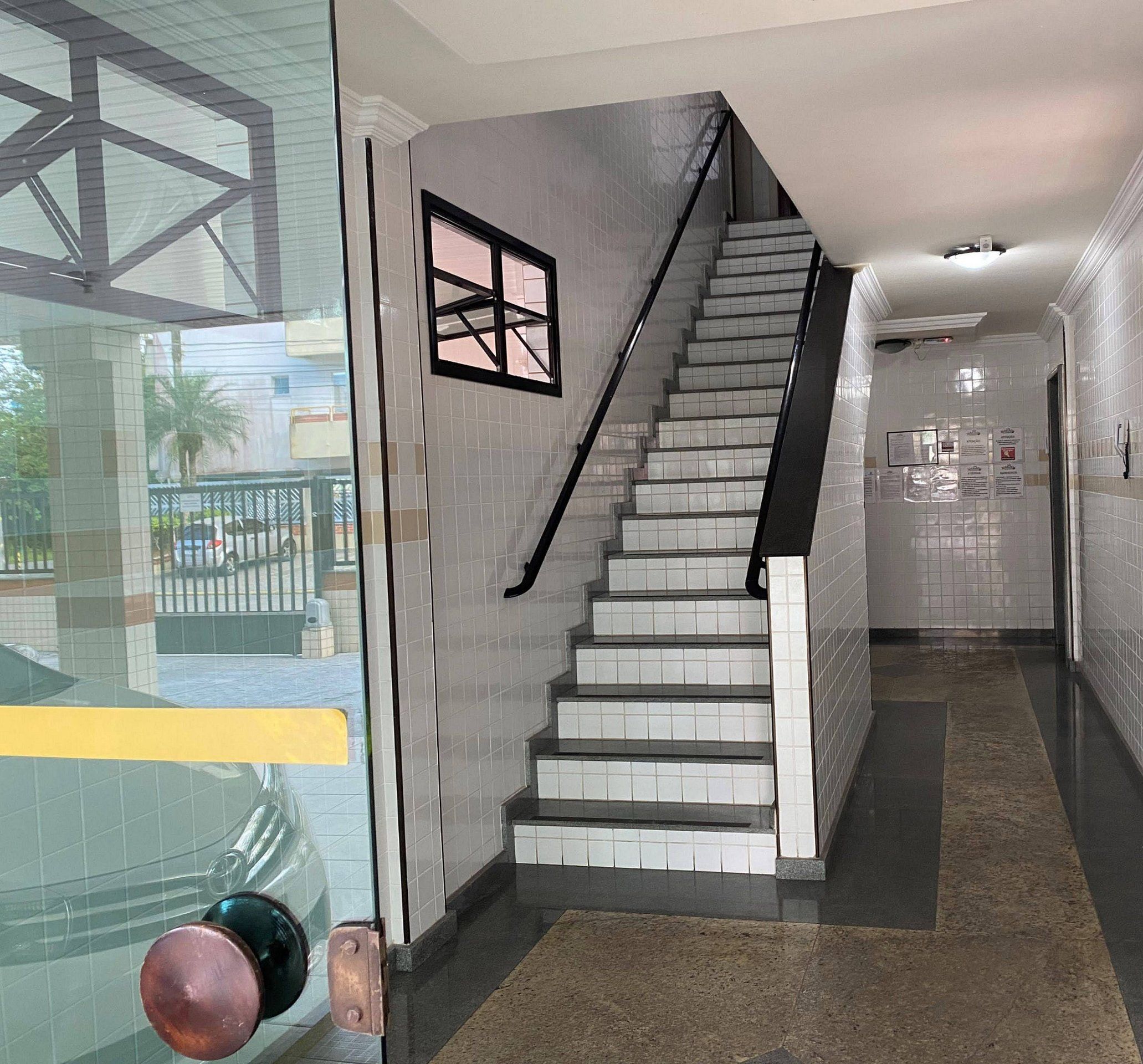 A modern interior with a staircase, tiled walls, and a glass door.