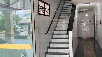 A modern interior with a staircase, tiled walls, and a glass door.