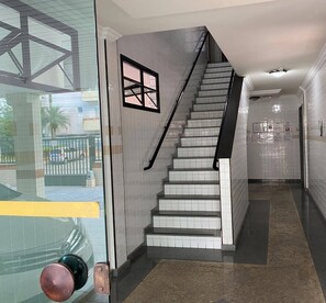 Un interior moderno con una escalera, paredes de azulejos y una puerta de cristal.