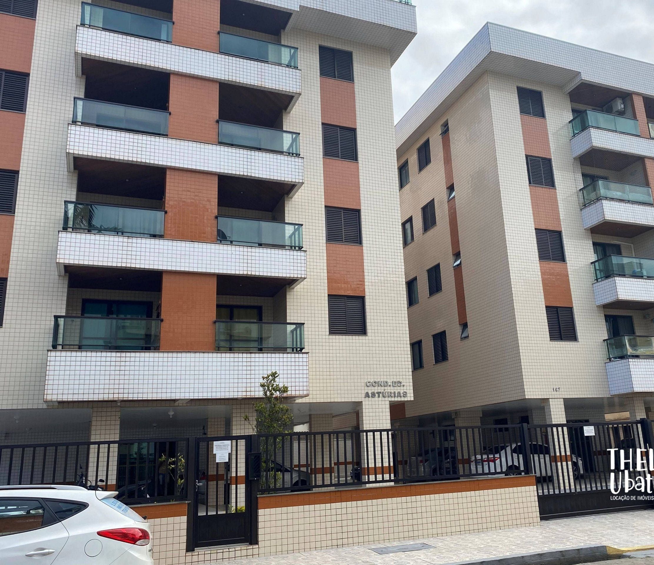 A multi-story residential building with balconies, a gated parking area, and a sign indicating a location for temporary vehicle storage.