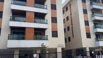 A multi-story residential building with balconies, a gated parking area, and a sign indicating a location for temporary vehicle storage.