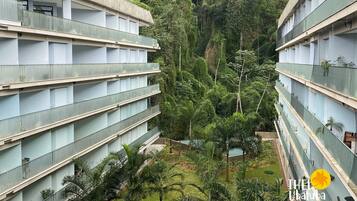 A multi-story hotel with balconies, surrounded by lush greenery and a central courtyard.