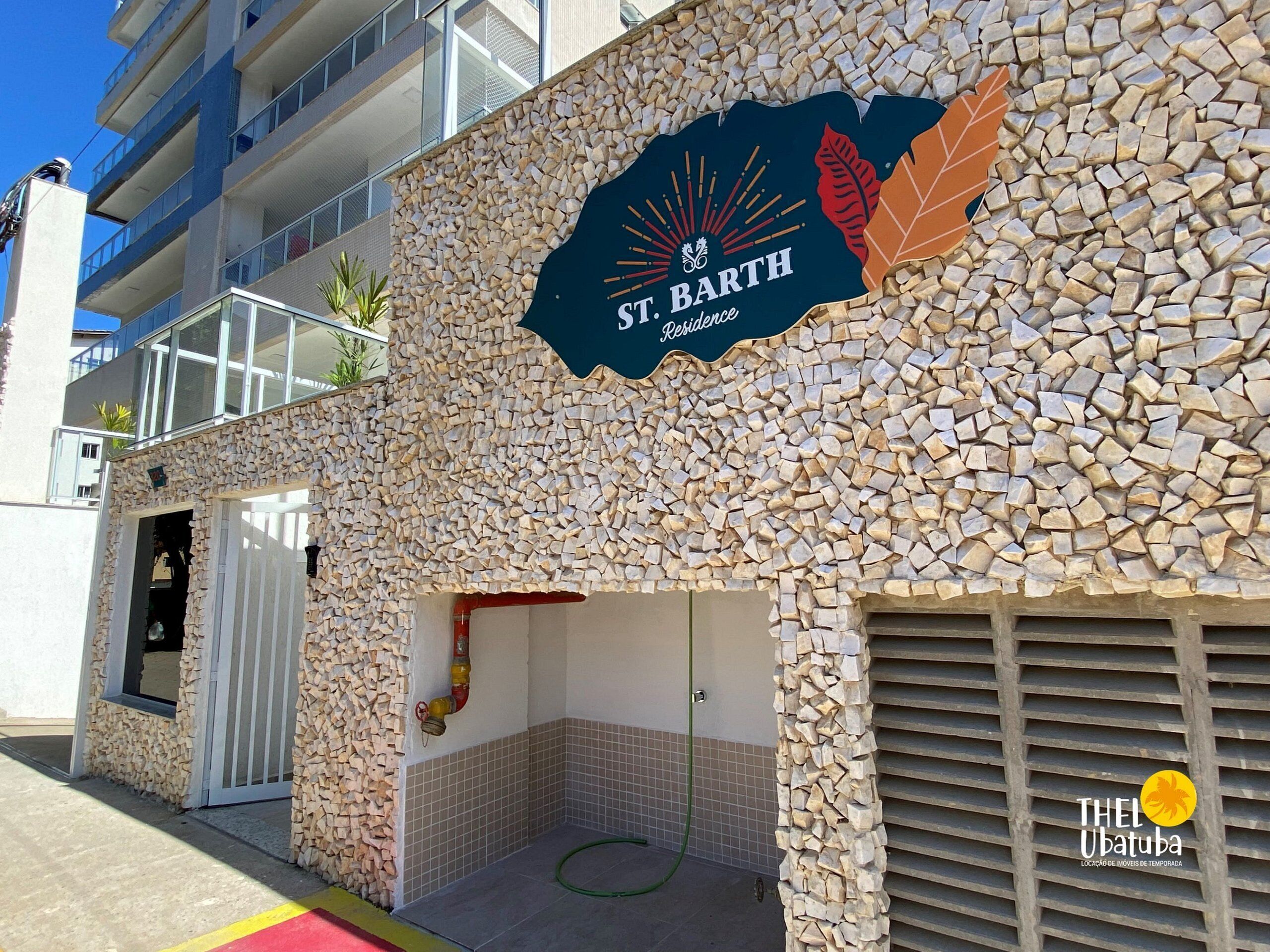 Eine Gebäudefassade mit steinernen Mosaik-Details, einem Schild für St. Barth Residence und dem Logo von The Ubatuba.