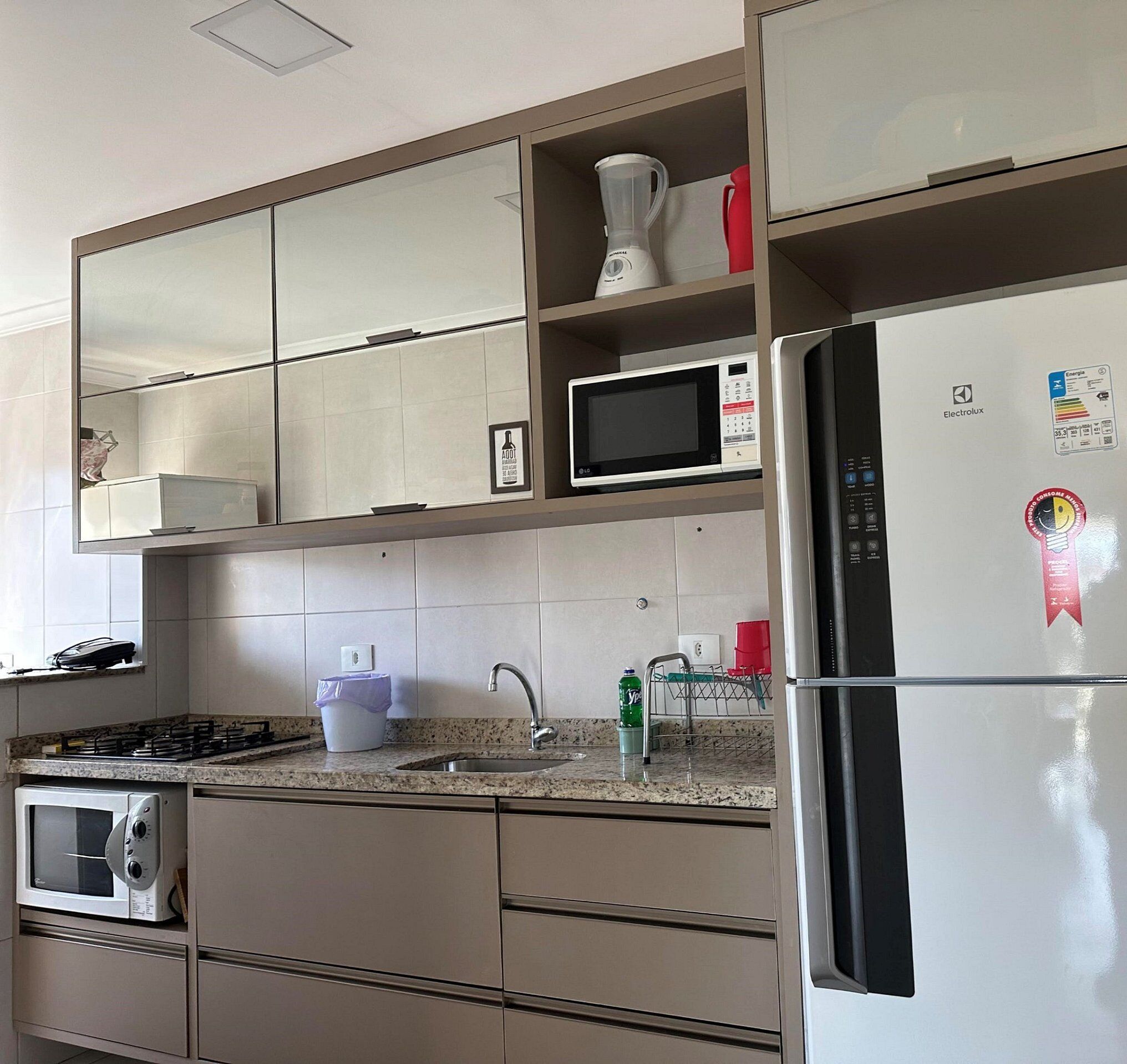 Una cocina moderna con microondas integrado, refrigerador, estufa y lavaplatos.
