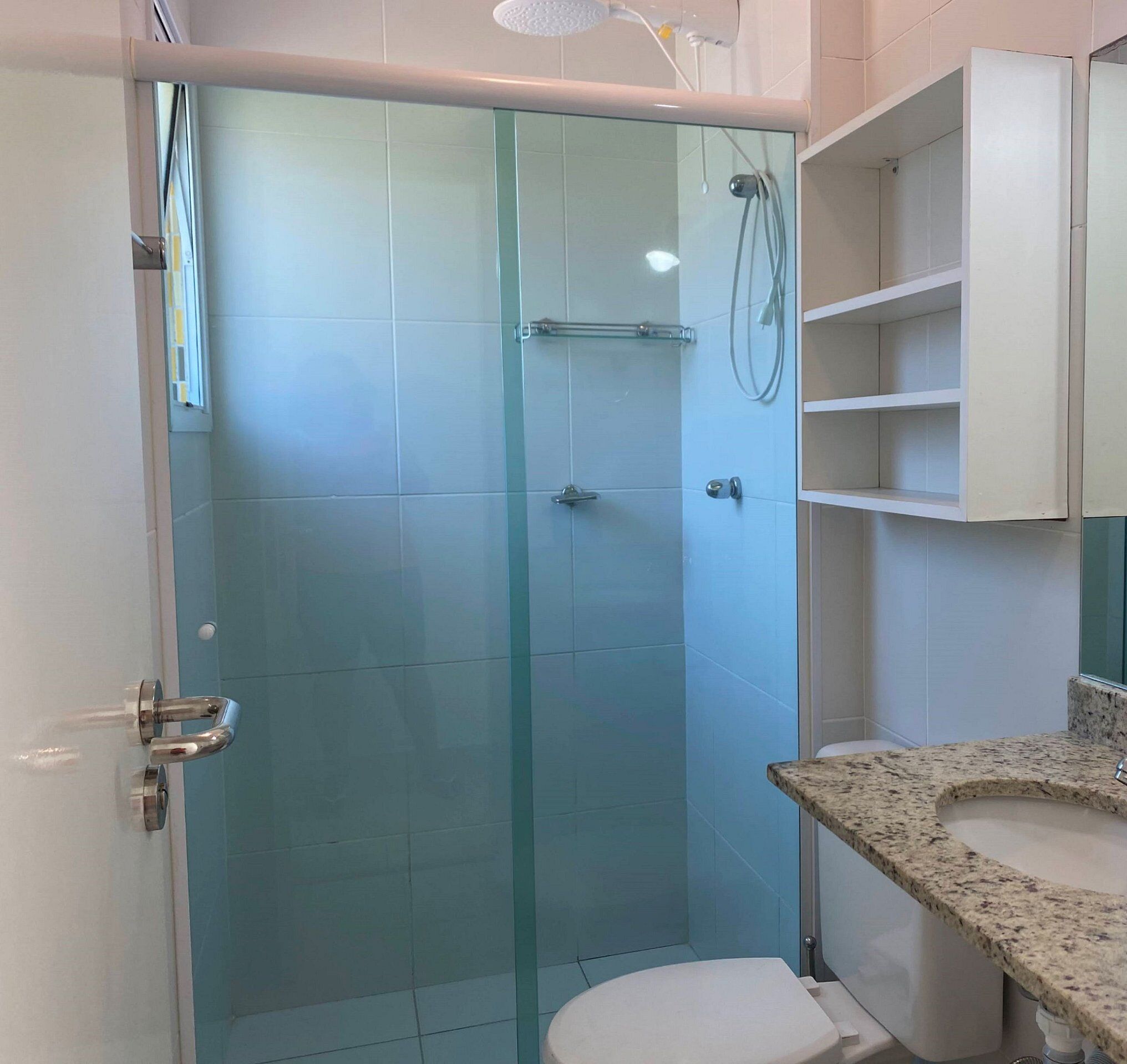 Un baño con ducha de vidrio, inodoro y lavamanos con encimera de granito.