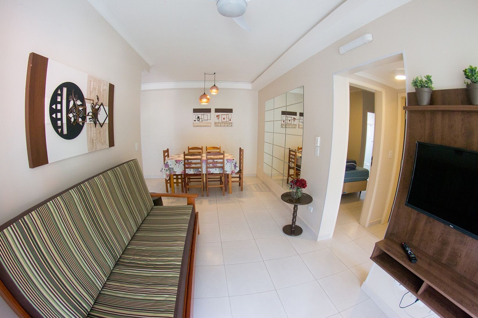 A living room with a sofa, dining table, chairs, a TV, and a ceiling fan.
