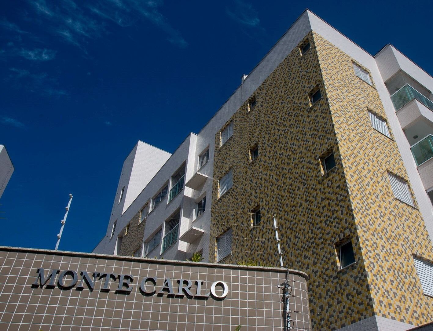 A building with a patterned facade and the name "MONTECARLO" on the ground floor.