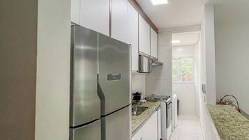 Uma cozinha moderna com eletrodomésticos de aço inoxidável, armários brancos e piso ladrilhado.