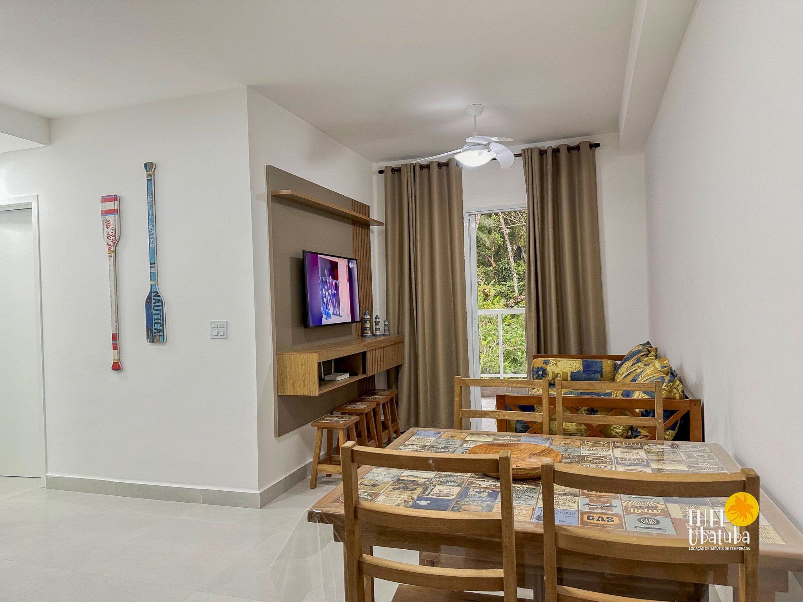 Uma sala de estar moderna com televisão, móveis de madeira e uma janela com cortinas.