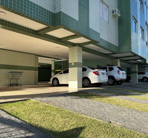 Uma área de estacionamento com dois carros brancos estacionados sob uma cobertura.