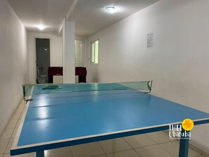 A room with a blue pool table, white walls, and a visible door leading to another room.