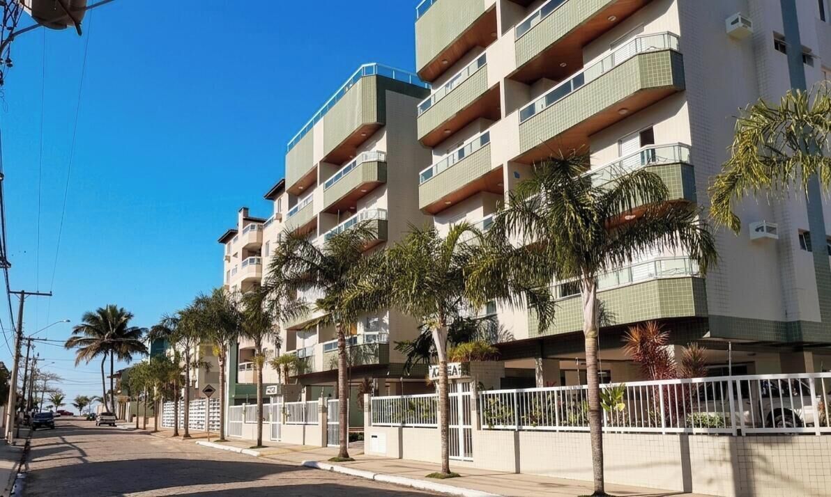 A multi-story residential building with balconies, palm trees, and a gated entrance.