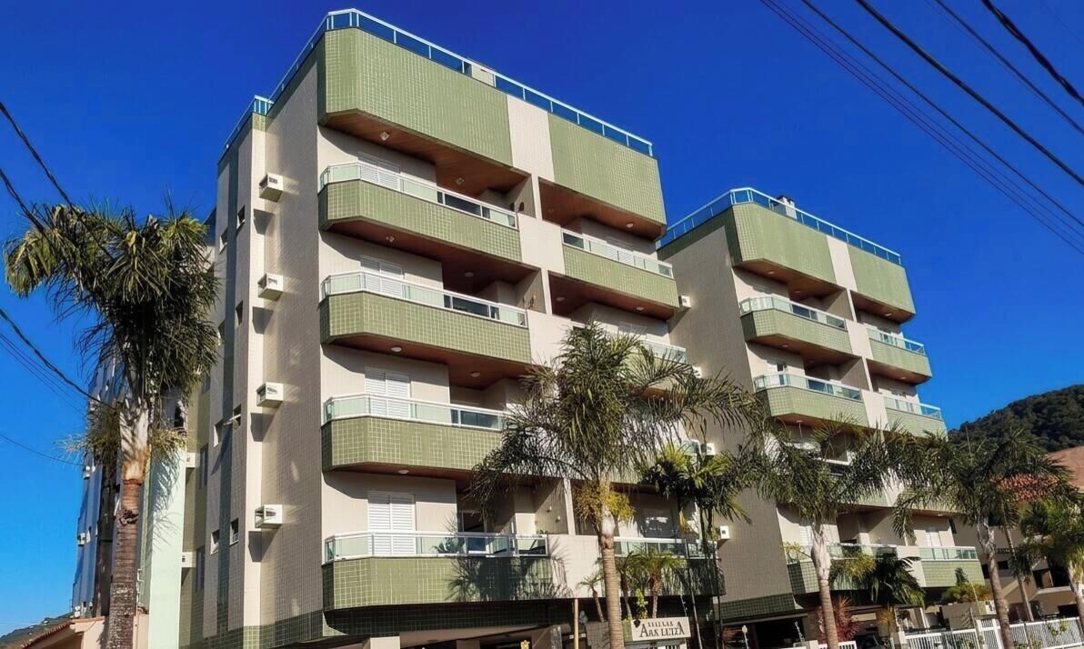 A multi-story building with balconies, palm trees, and a clear sky.