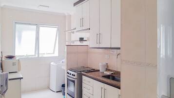 A kitchen with white cabinets, a stove, and a window.