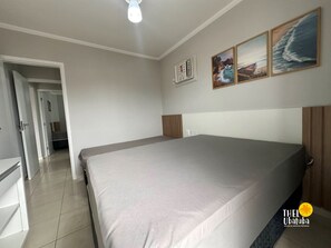Une chambre avec un grand lit, un luminaire au plafond et trois tableaux encadrés accrochés au mur.