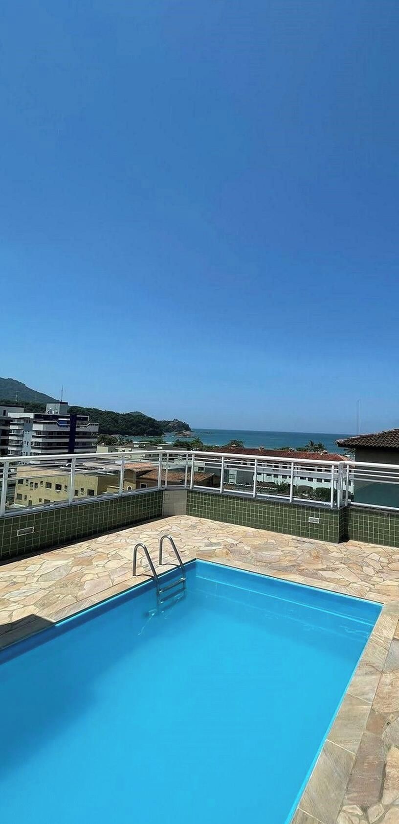 Una piscina en la azotea con vistas despejadas al mar y montañas al fondo.